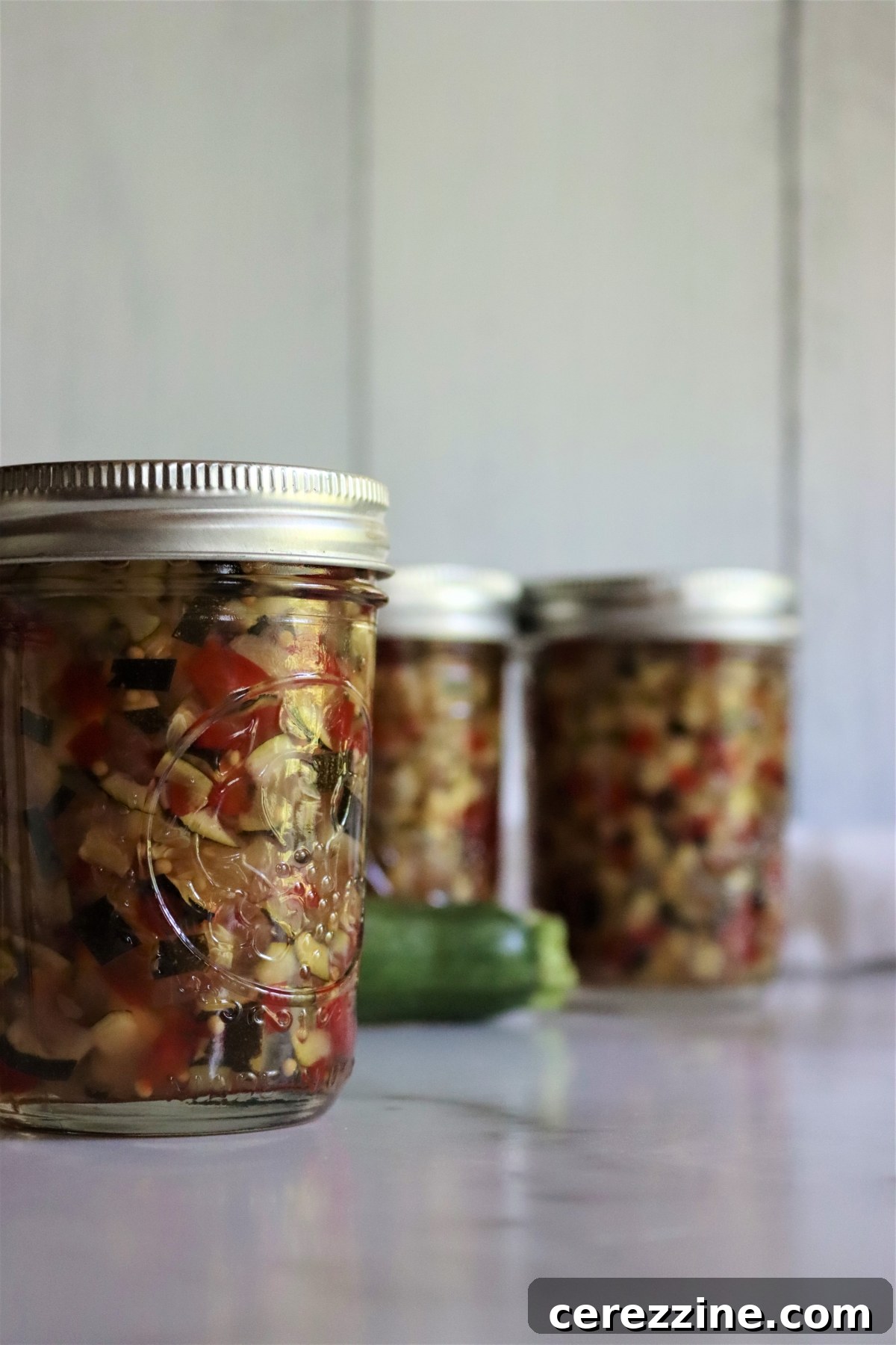Several jars of homemade zucchini relish on a shelf