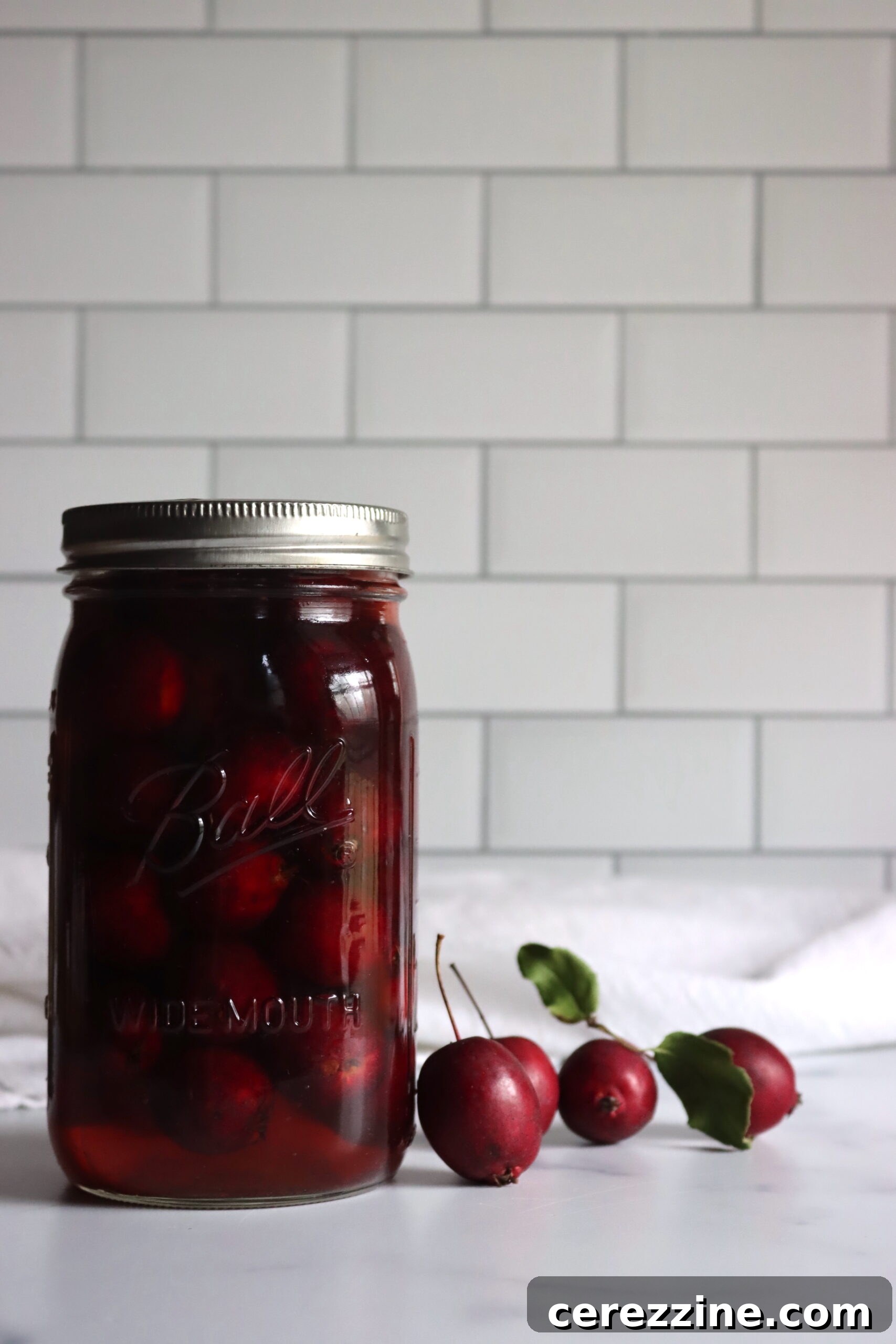 Fifty Varied Pickle Recipes From Asparagus To Zucchini 3 Close-up of glass jars filled with spiced pickled crabapples, showcasing their vibrant color and readiness for storage.