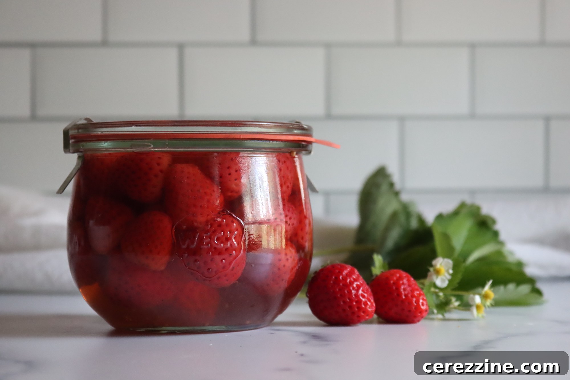 Fifty Varied Pickle Recipes From Asparagus To Zucchini 26 A glass jar filled with whole pickled strawberries, some with their green caps attached.