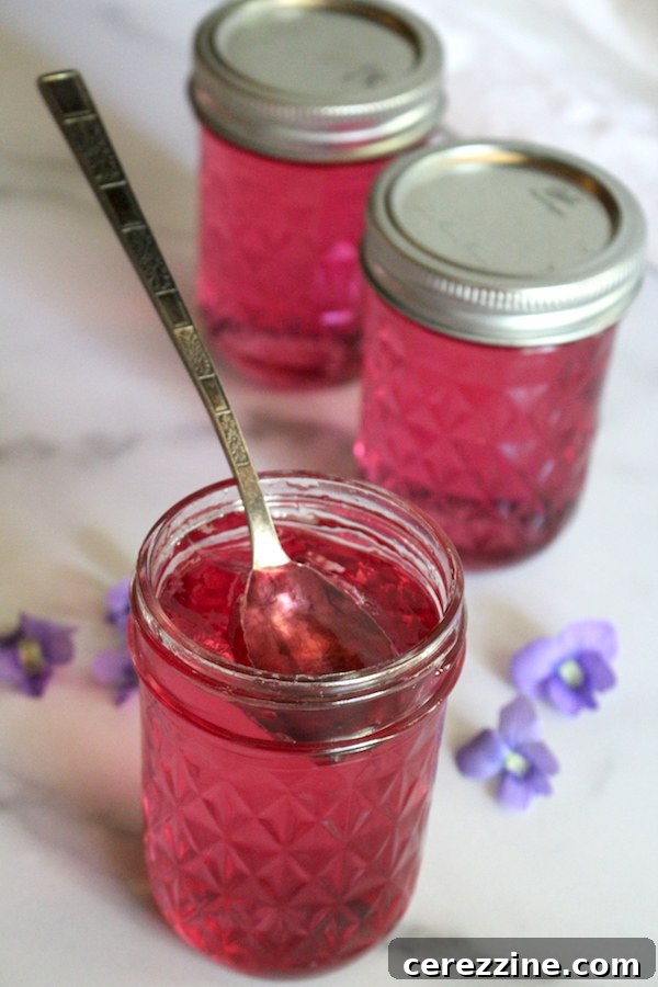 A jar of vibrant violet jelly, thick and smooth, with a spoon inserted, ready to be spread.