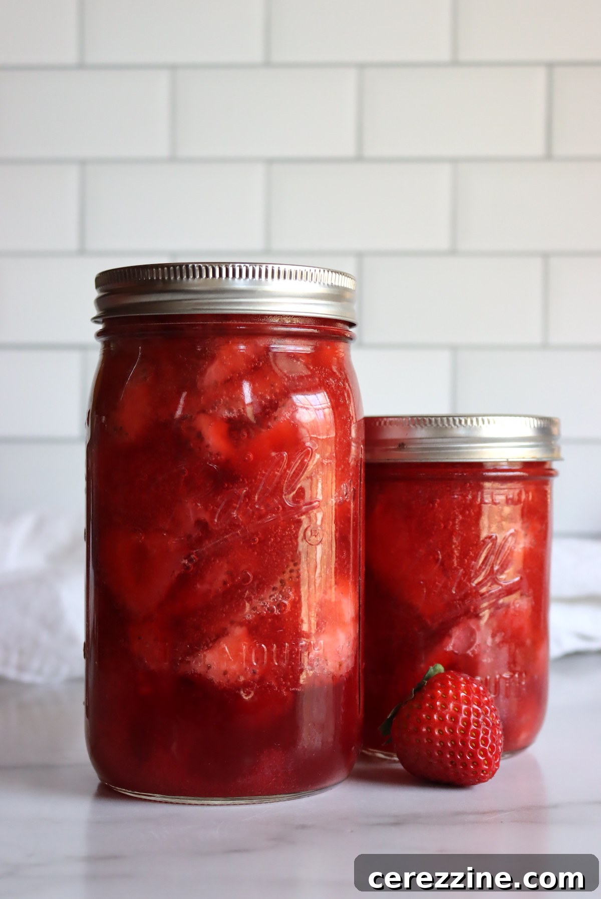 Freshly canned strawberry pie filling jars cooling on the counter