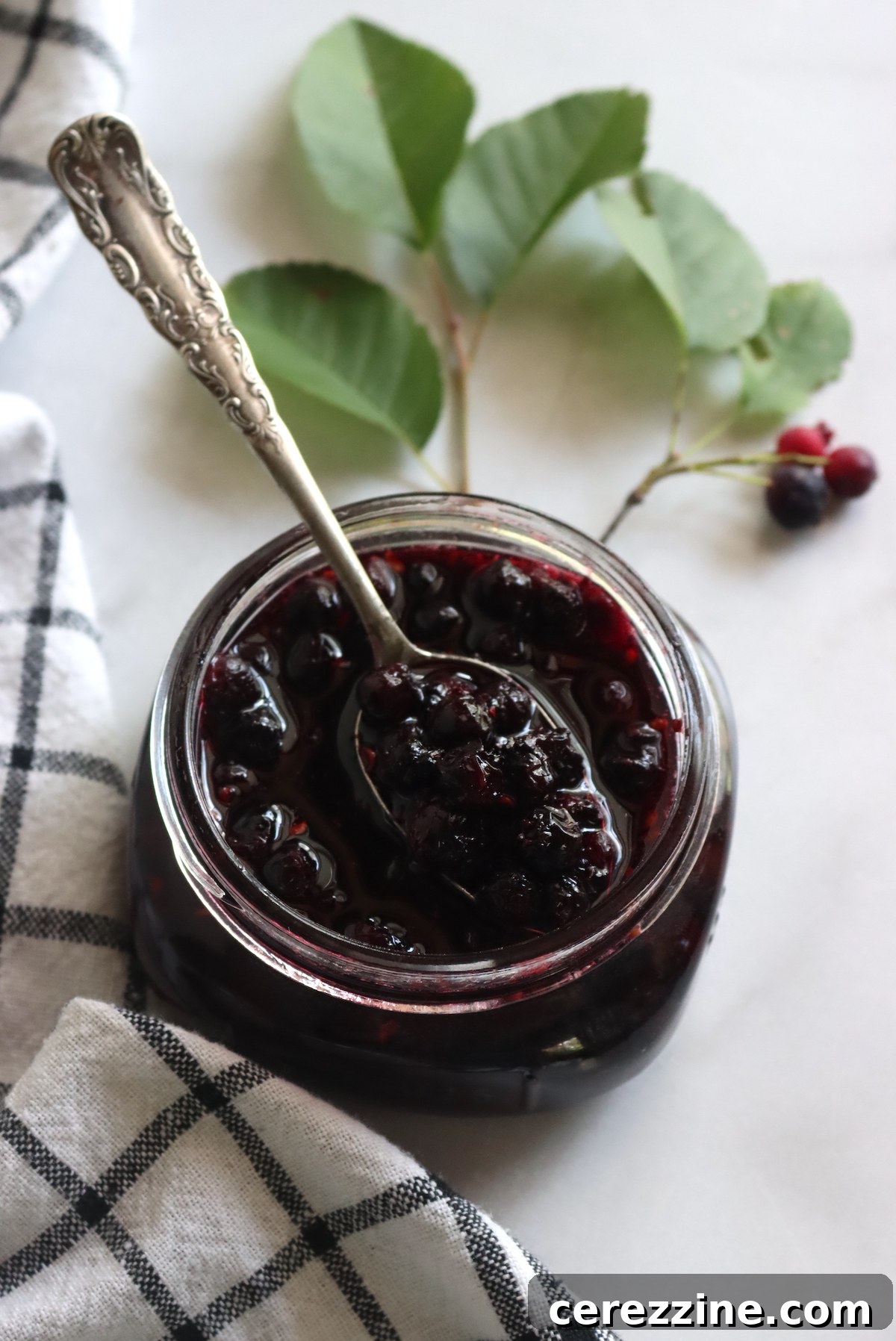 A pot of simmering Saskatoon jam on a stove, showing the vibrant color and texture of the berries.