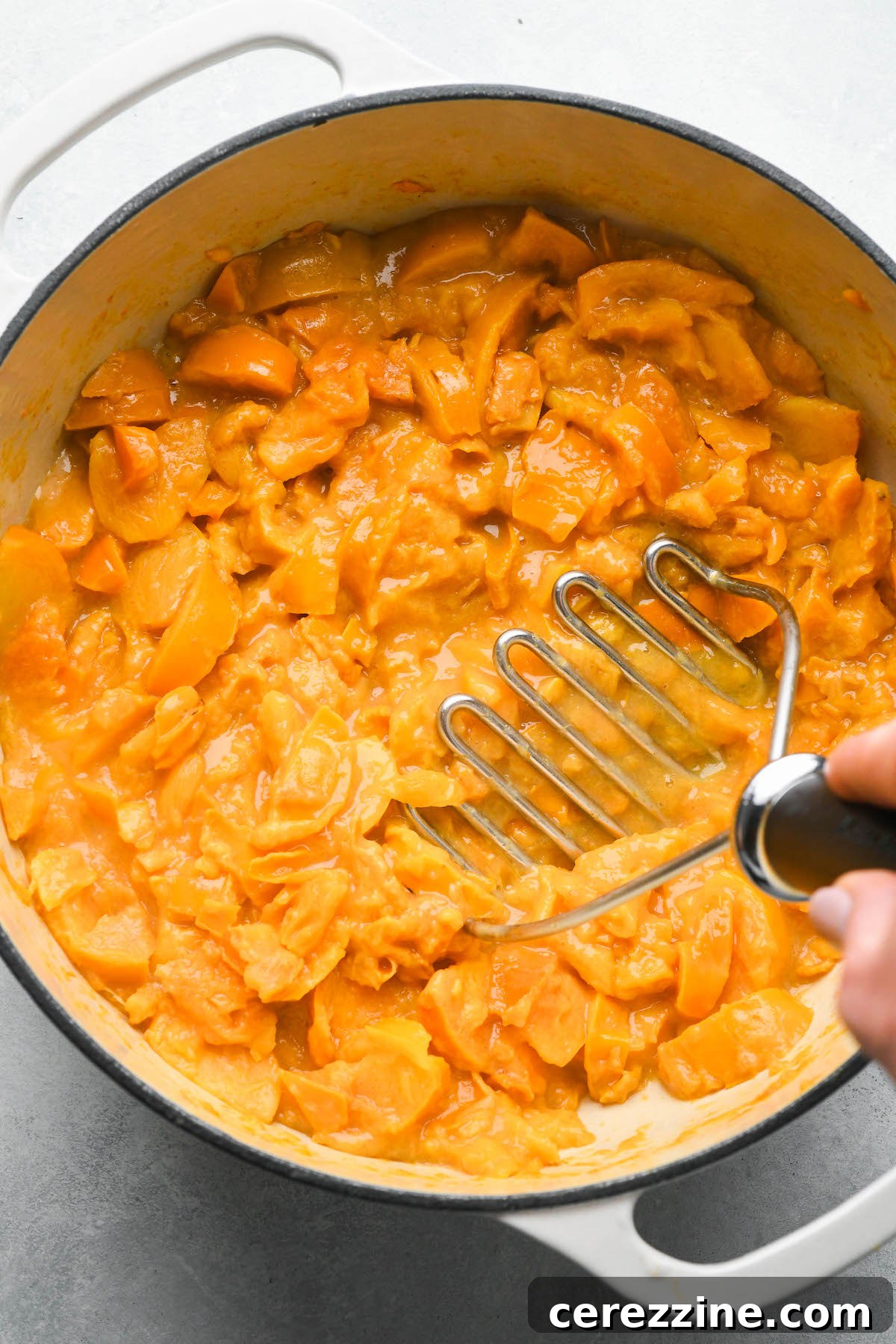 Mashed persimmons cooking down in a Dutch oven, preparing for sugar addition.