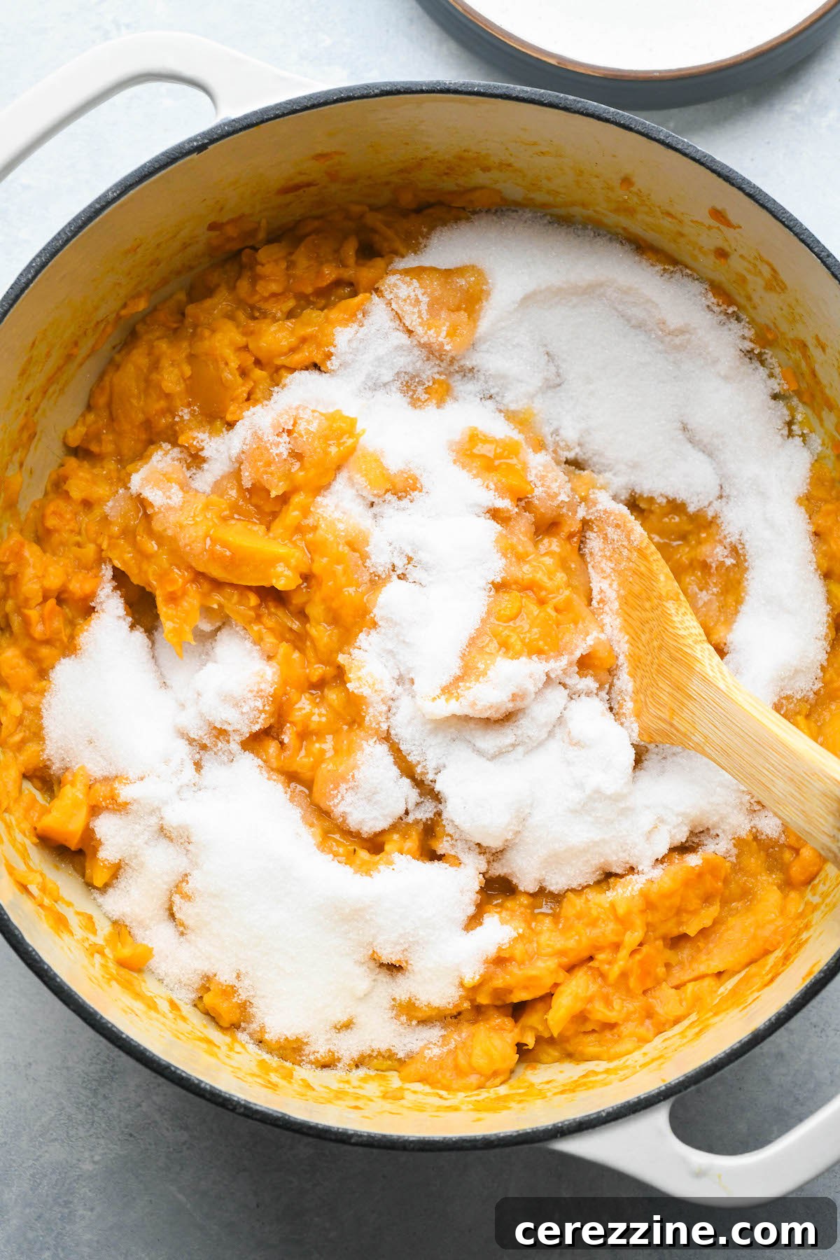 Sugar being stirred into the cooked persimmon pulp for jam.