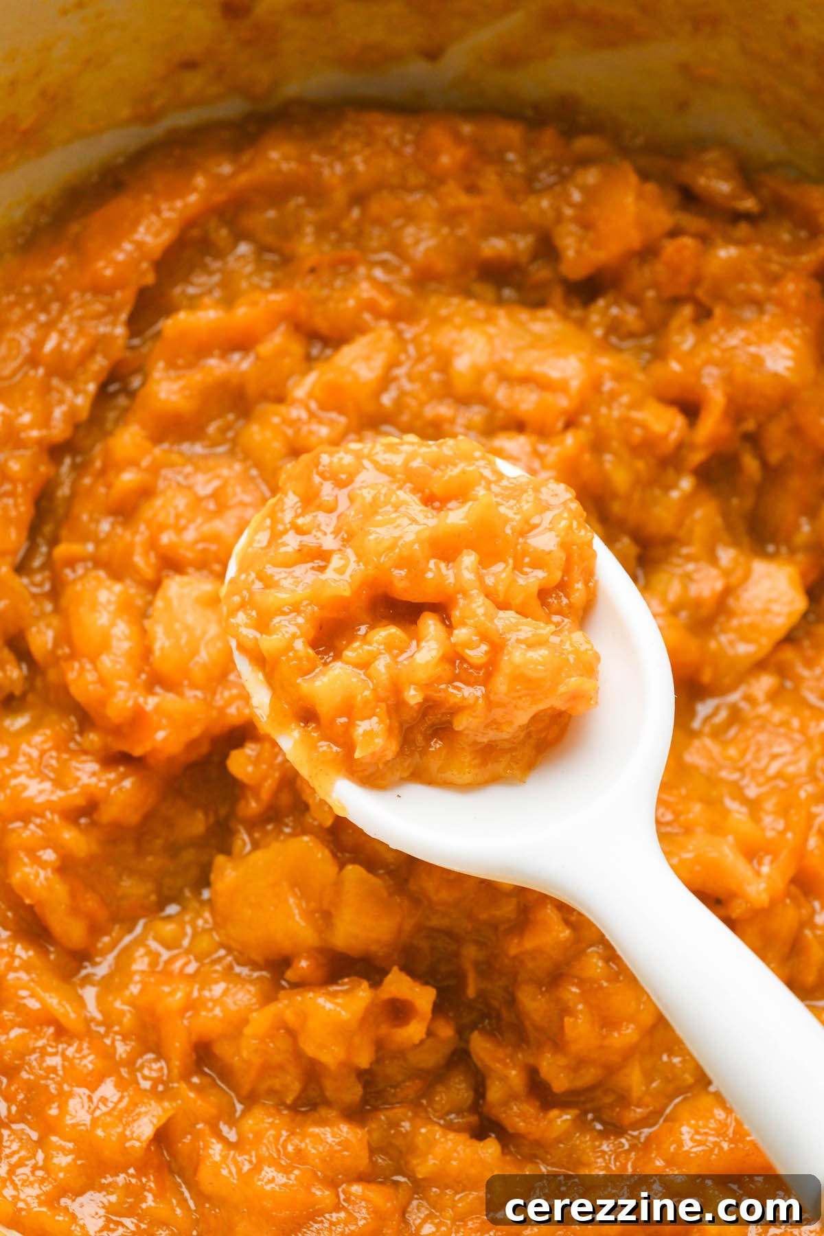 Persimmon jam simmering and thickening in a pot.