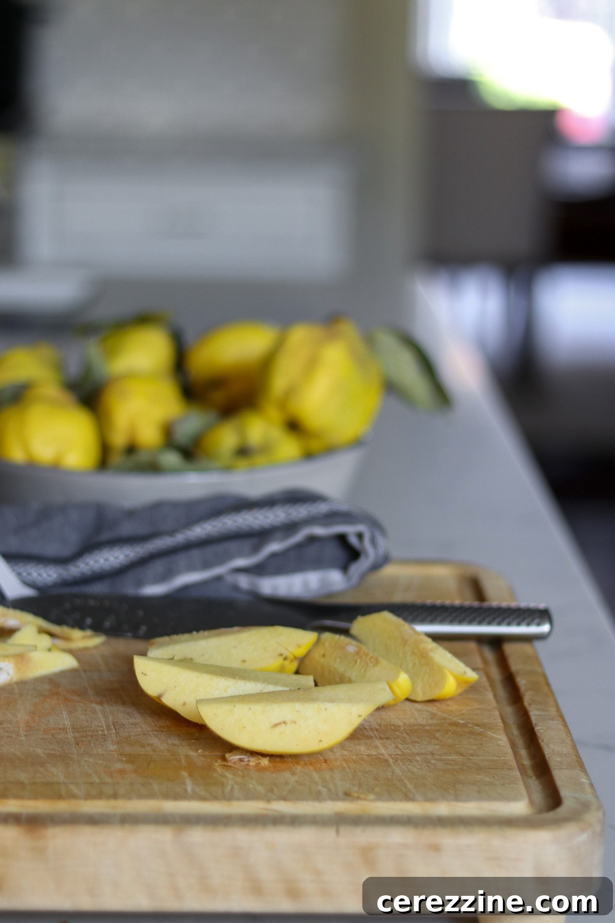 A person carefully peeling and coring a quince on a cutting board, preparing it for jam.