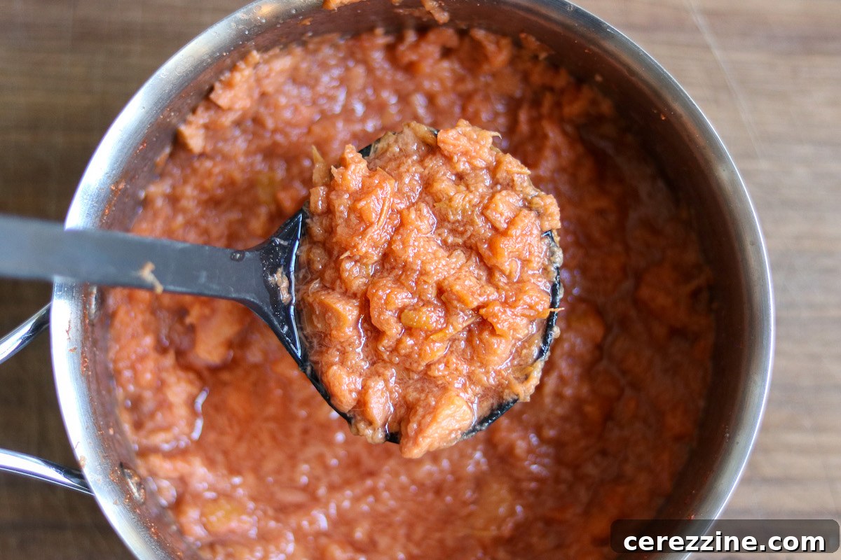 Close-up of quince jam being stirred in a pot, demonstrating its rich color and smooth consistency.