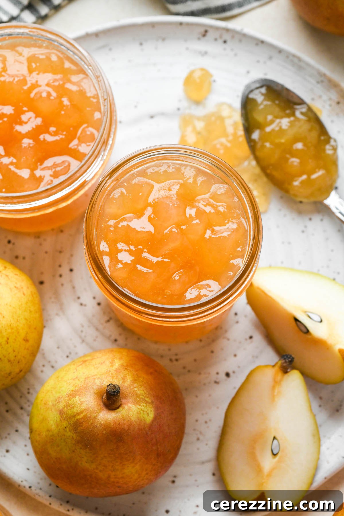 Sun Kissed Pear Jam 11 A jar of homemade pear jam on a wooden surface.