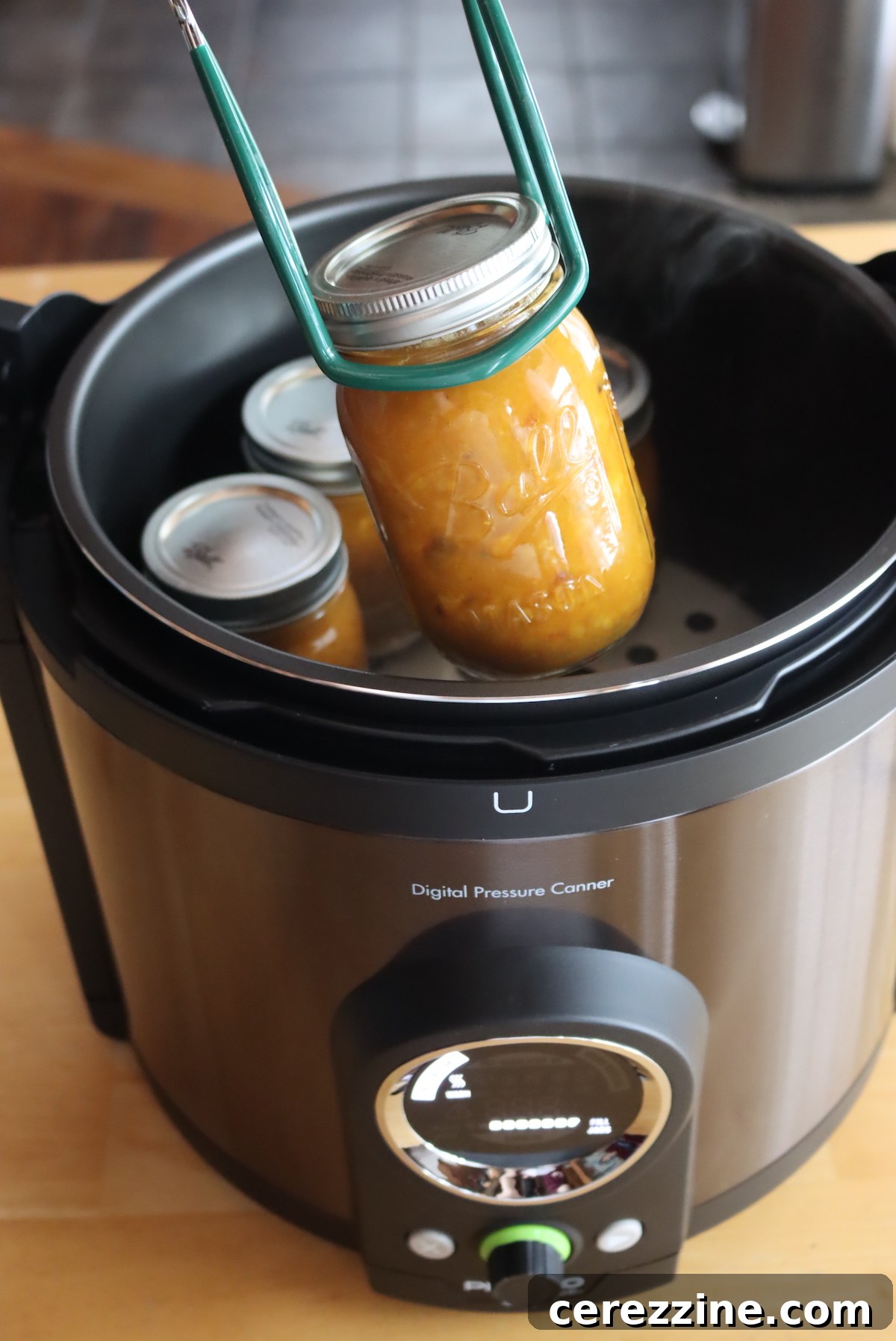 Canning jars filled with food being carefully loaded into the digital pressure canner.