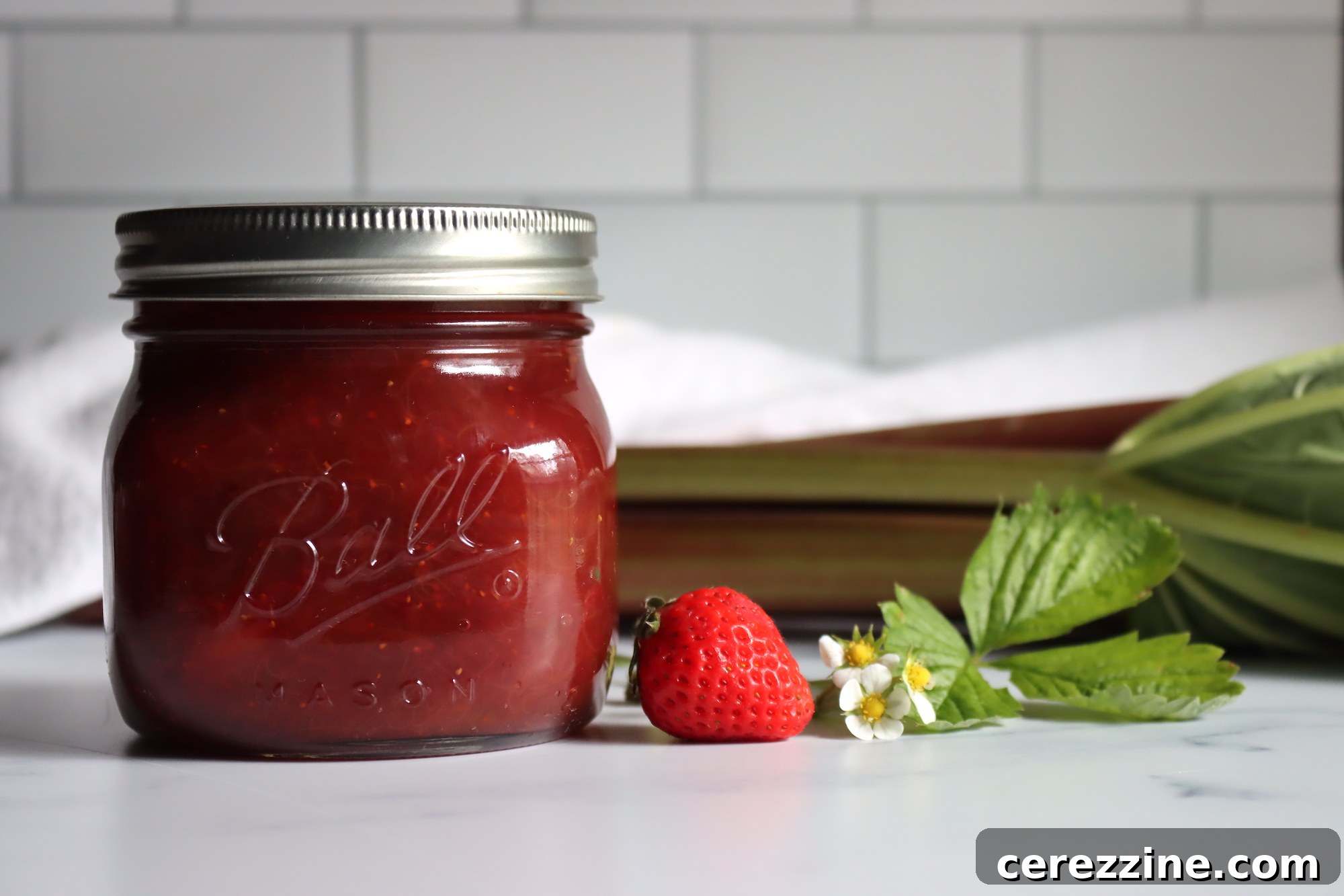 Canned Strawberry Rhubarb Jam jars cooling on a counter after water bath processing.