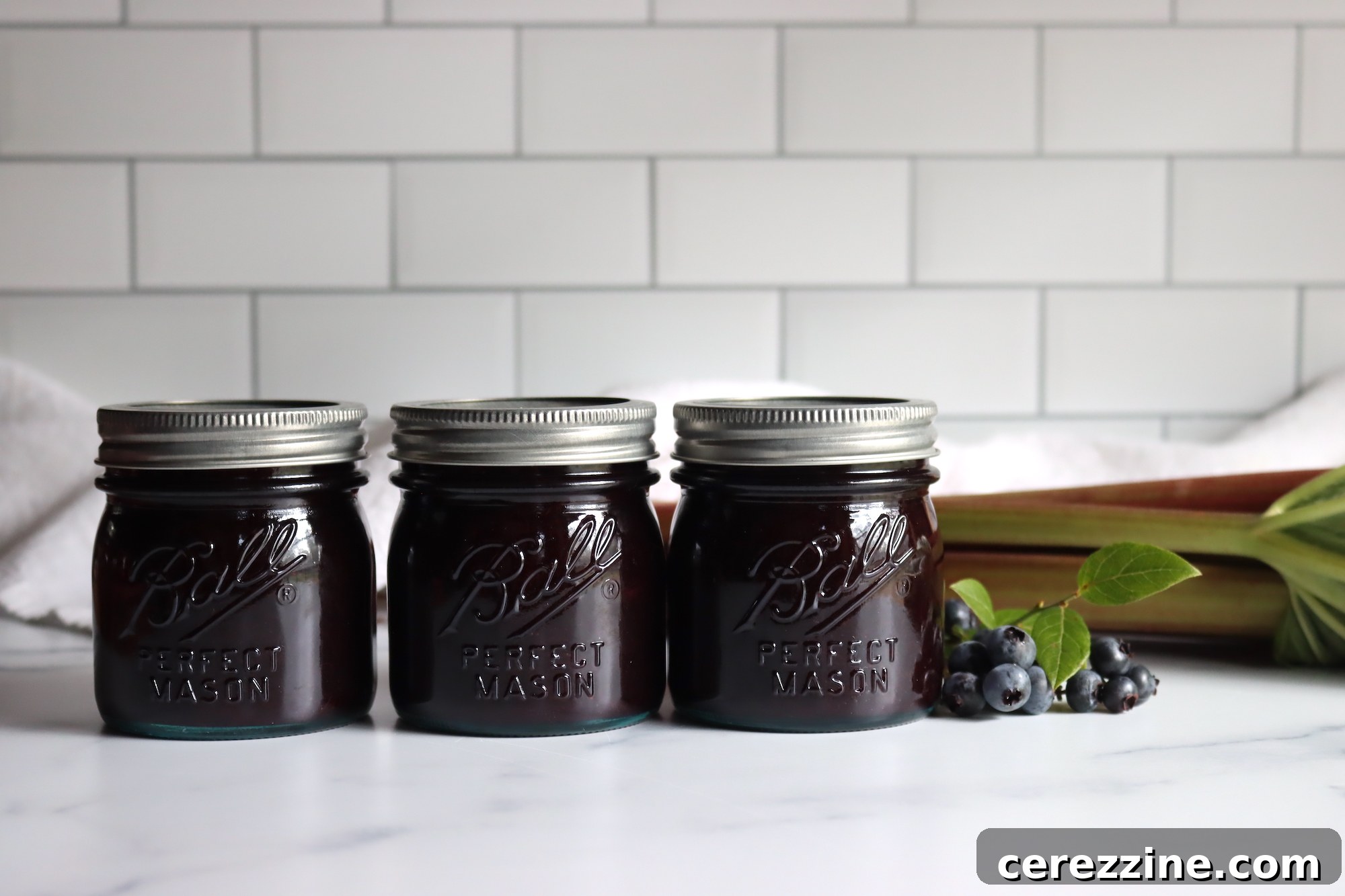 Sealed jars of homemade blueberry rhubarb jam cooling on a counter after canning
