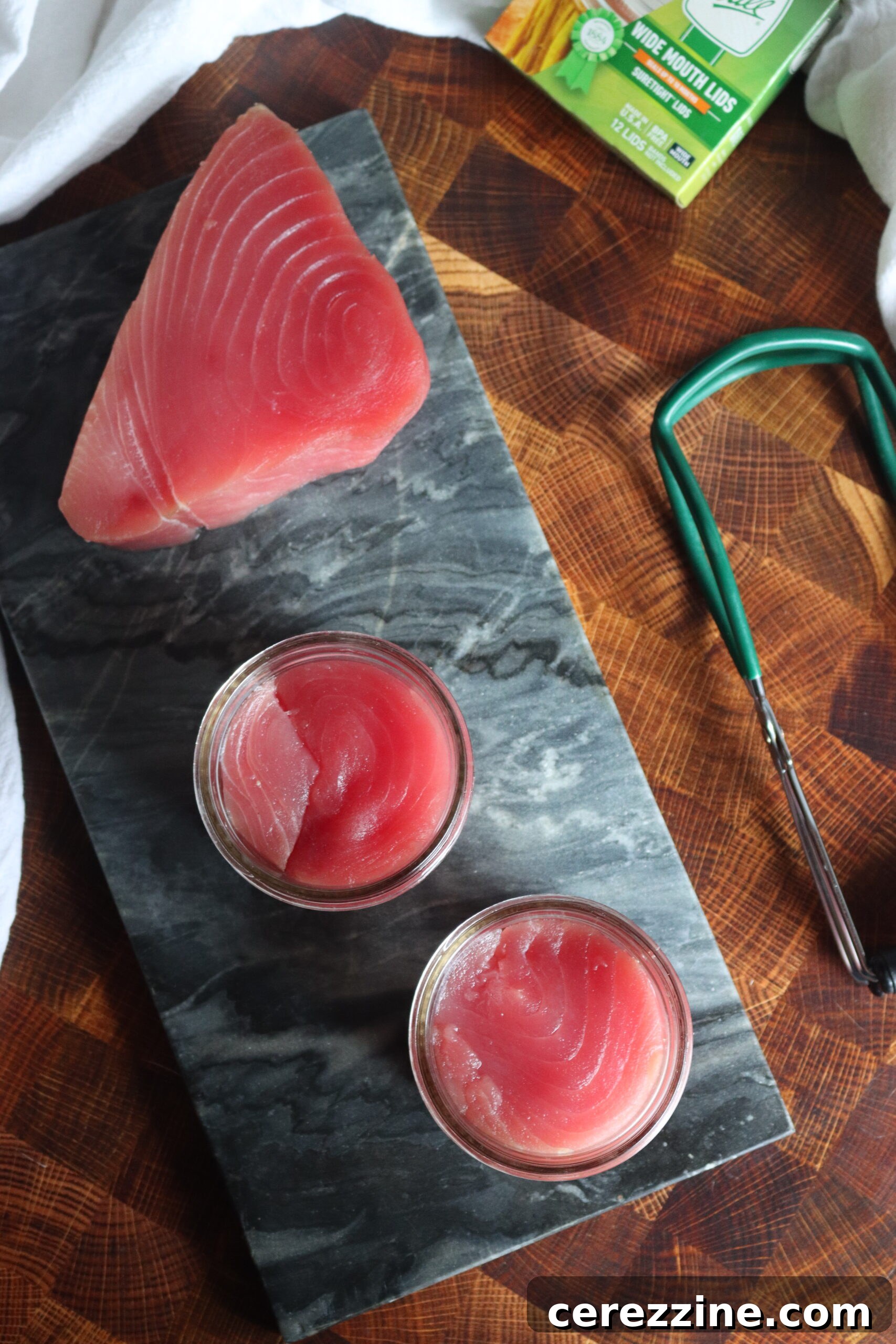 Canning Tuna - A close-up view of tuna chunks being carefully placed into canning jars, alongside oil or water.