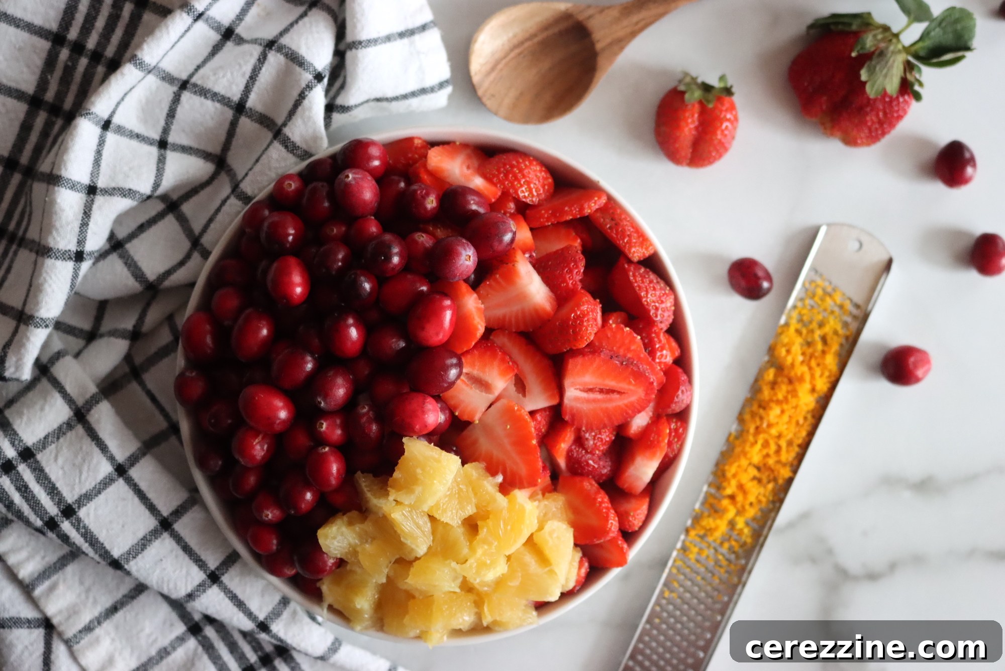 Fresh cranberries, strawberries, orange, sugar, and cinnamon stick laid out for Christmas Jam.
