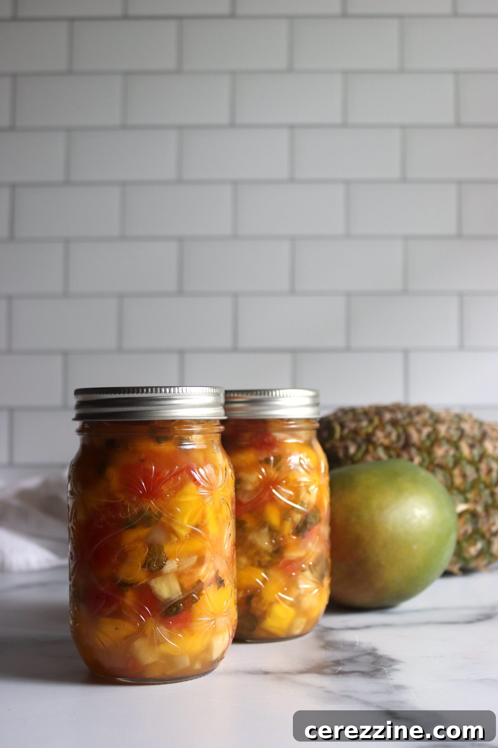 A jar of homemade Pineapple Mango Salsa with a label, ready for the pantry.