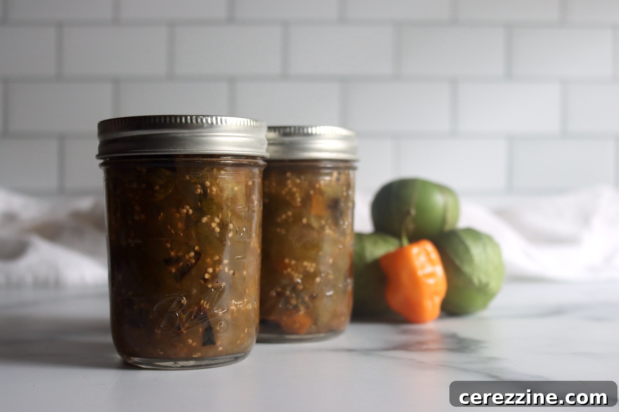 Close-up of roasted tomatillos and habanero peppers, showing char marks.