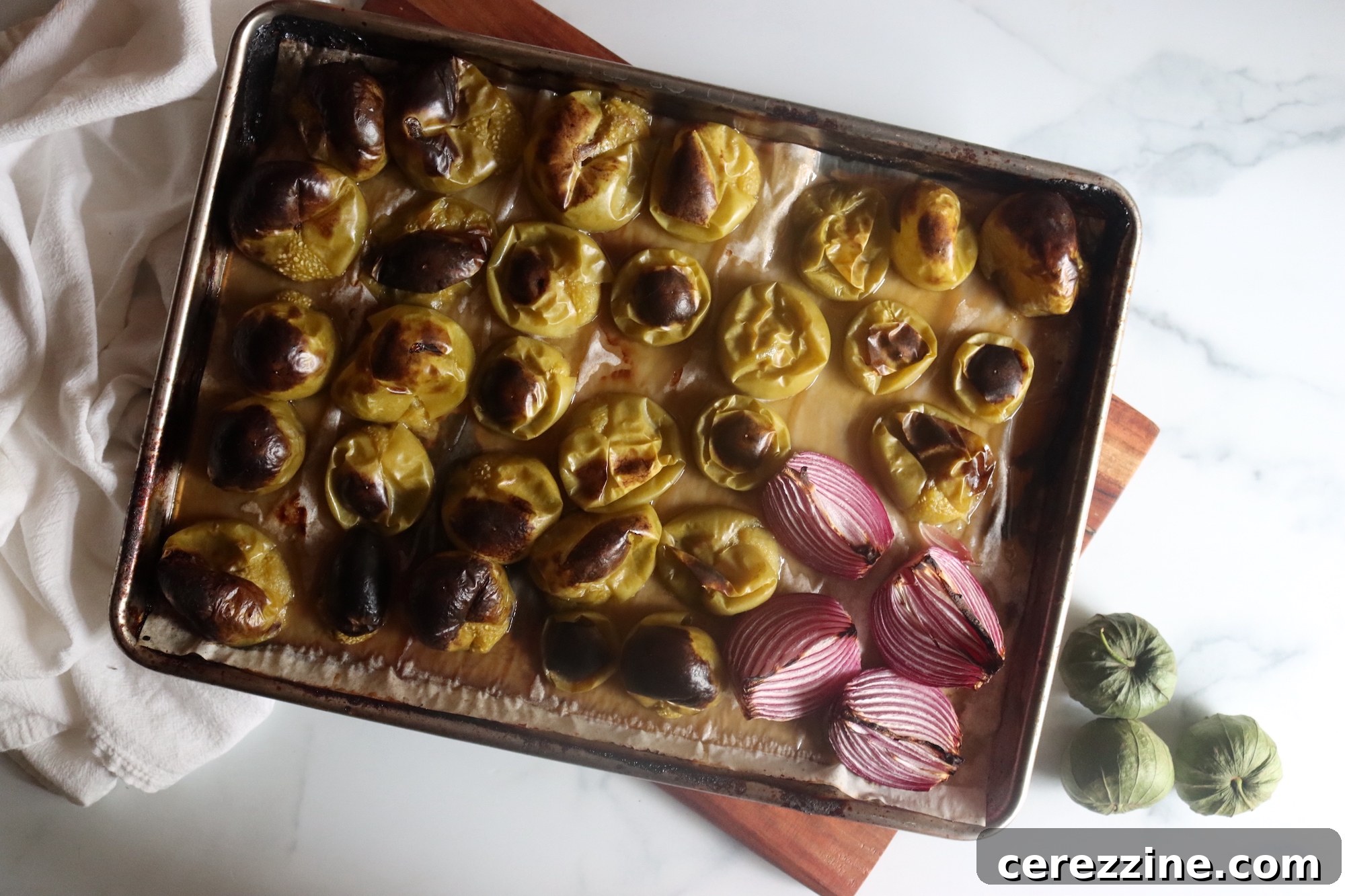 Chopped roasted tomatillos and onions on a cutting board, ready for the pot.