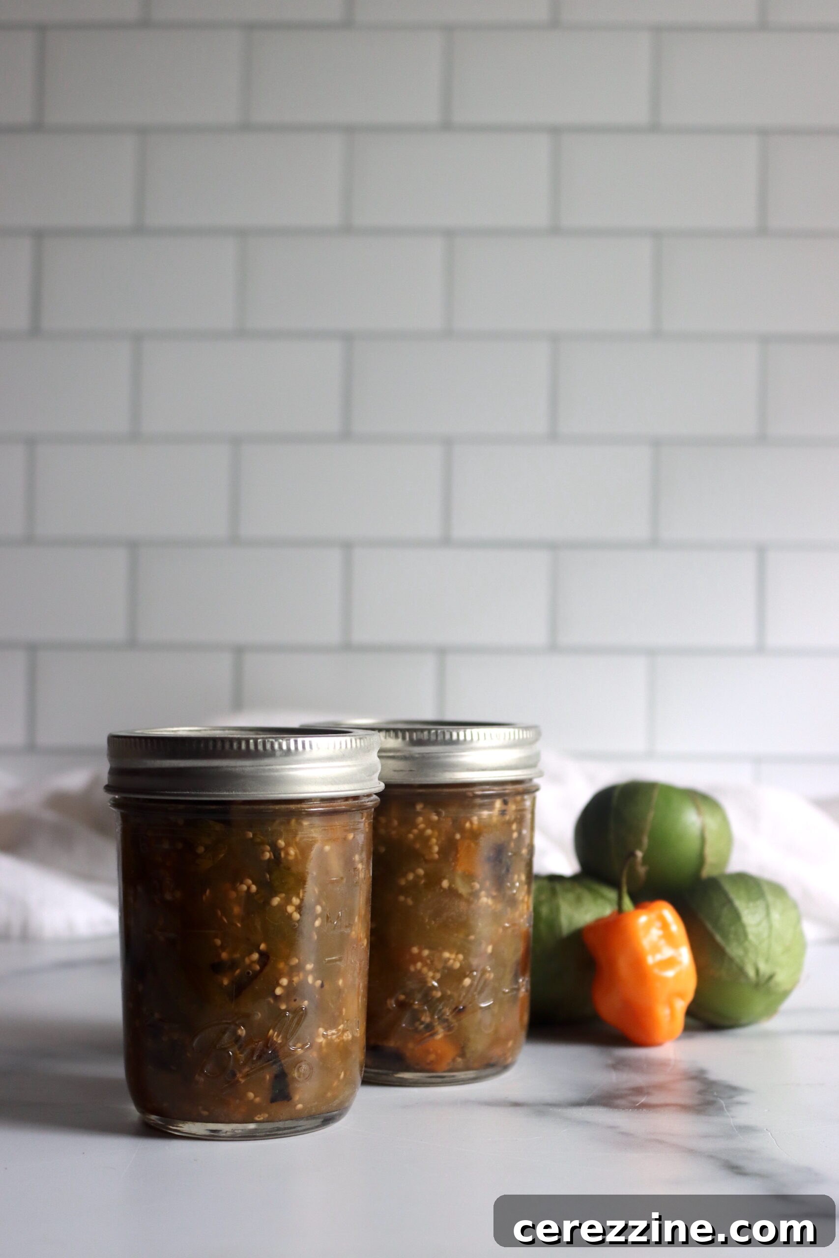 A row of freshly canned Tomatillo Habanero Salsa jars on a cooling rack.