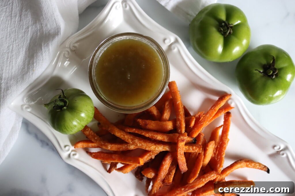Tangy Green Tomato Ketchup 6 Thickening green tomato ketchup bubbling gently in a large pot on the stove, showing its rich, reduced texture.