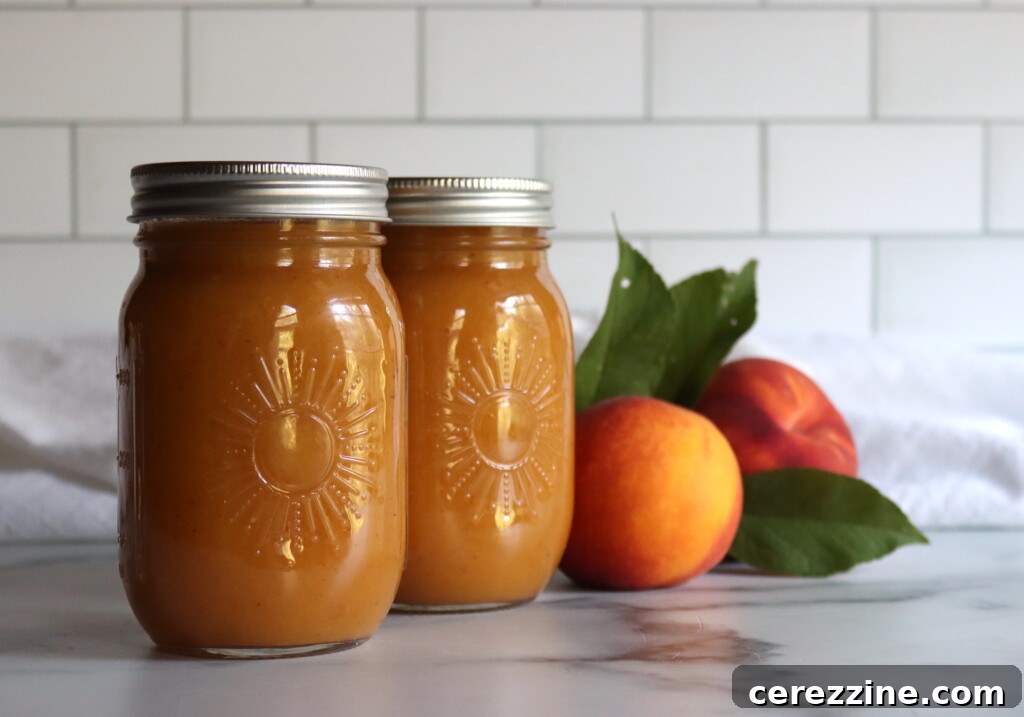 Two jars of peach nectar in sunshine jars on a white counter.