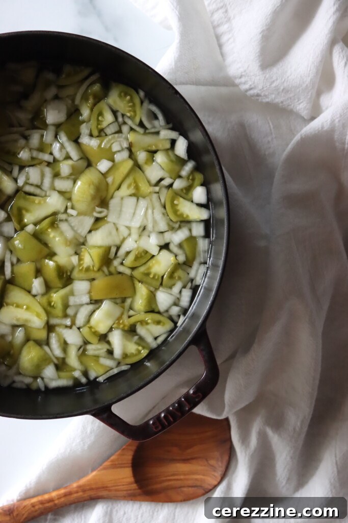 A large pot brimming with green tomatoes and onions, simmering gently in a flavorful vinegar solution, beginning its transformation into chow chow.