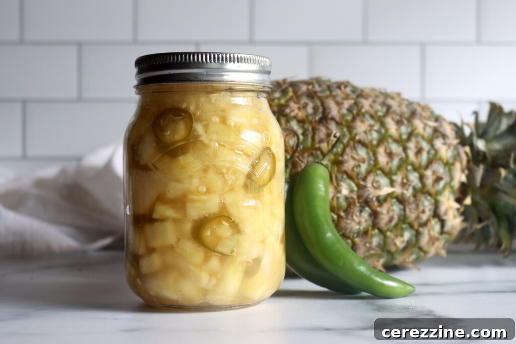 A jar of Spicy Pickled Pineapple slices, gleaming with delicious brine