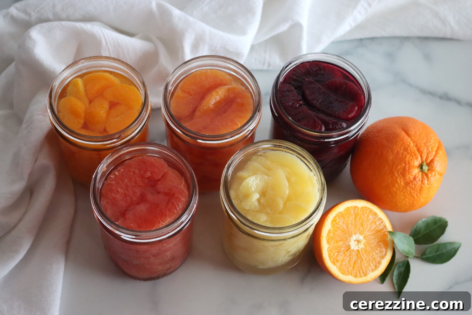 Jars of Canned citrus segments. From Left to right: Mandarins, cara cara oranges, blood oranges, grapefruit and lemons.