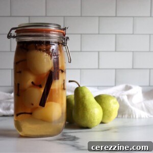 Homemade pickled pears in a jar on a white countertop.