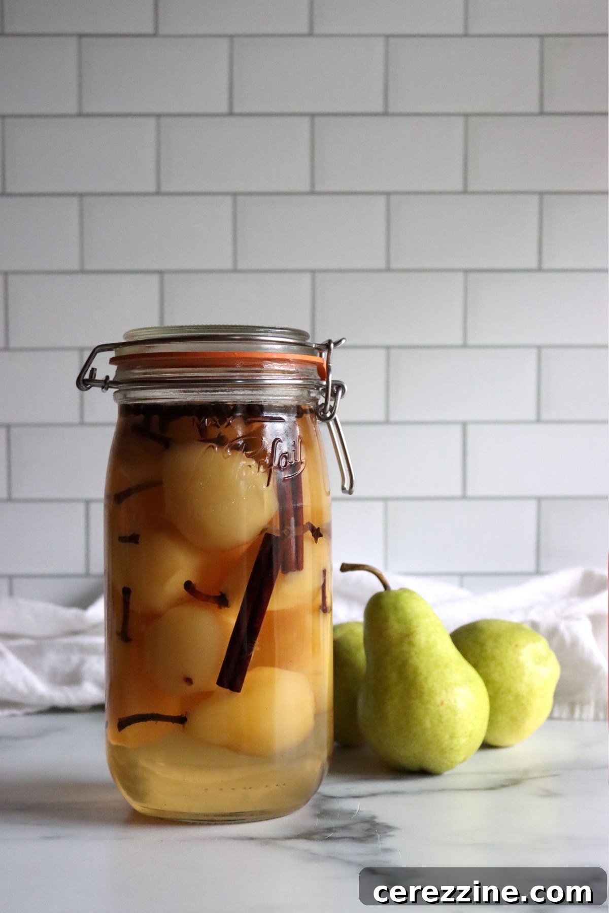 Orchard's Tangy Treasure 7 Pickled pears in a jar on a white table.