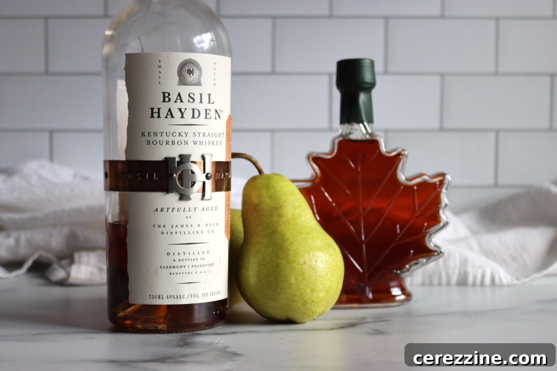 Ingredients laid out for Maple Bourbon Pear Butter, including fresh pears, maple syrup, and a bottle of bourbon.