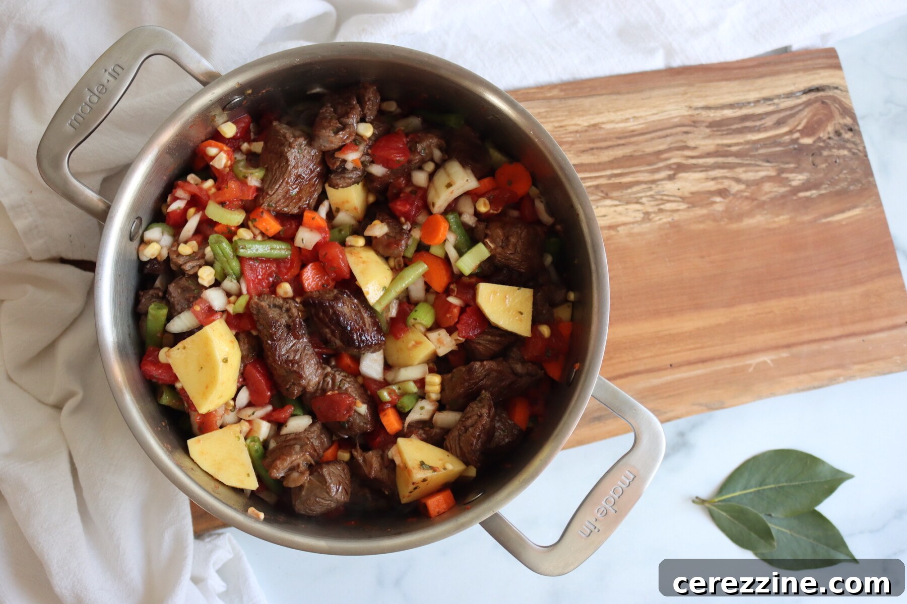 Vegetables and browned beef simmering in a pot