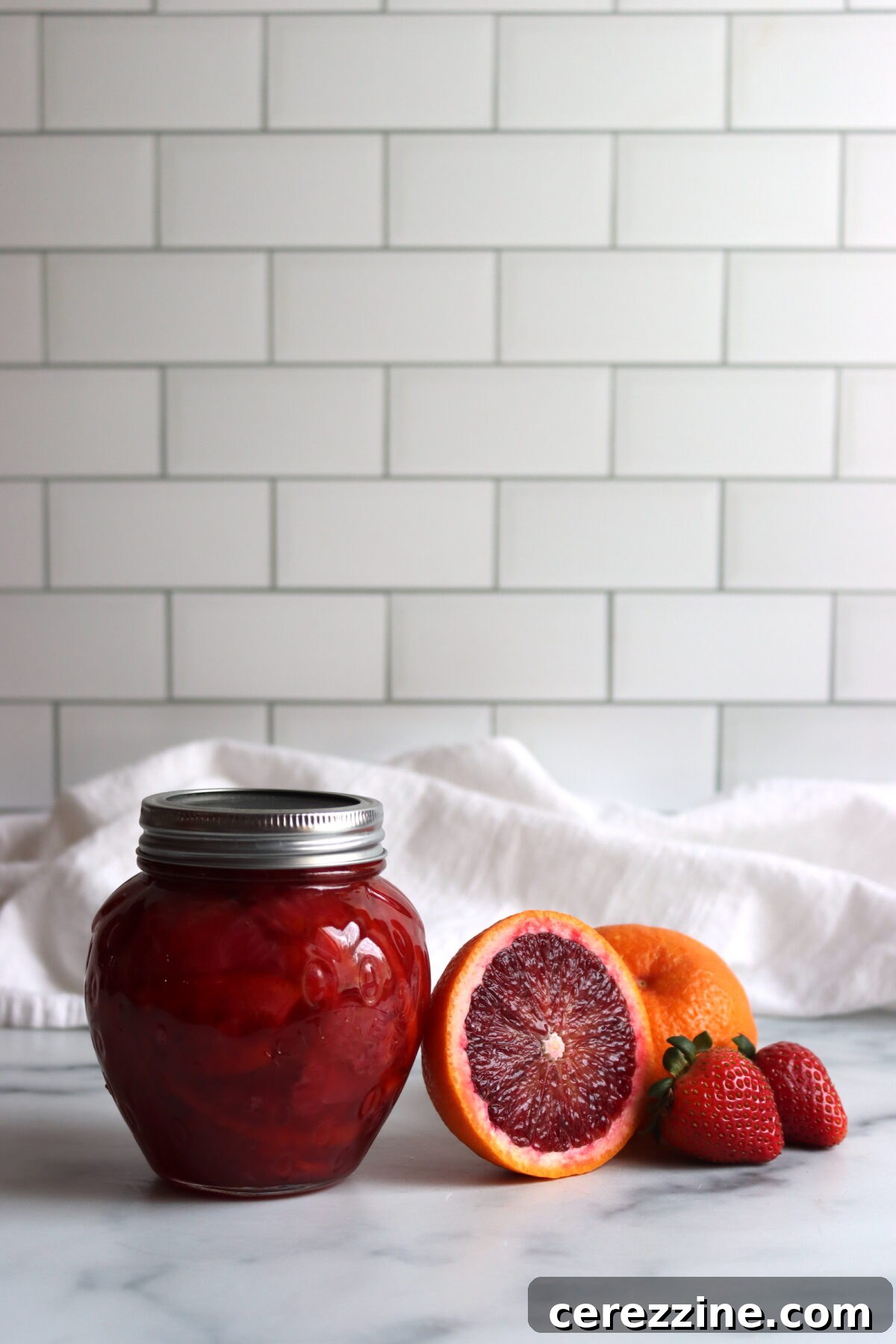 Finished jars of Strawberry Blood Orange Marmalade cooling on a counter