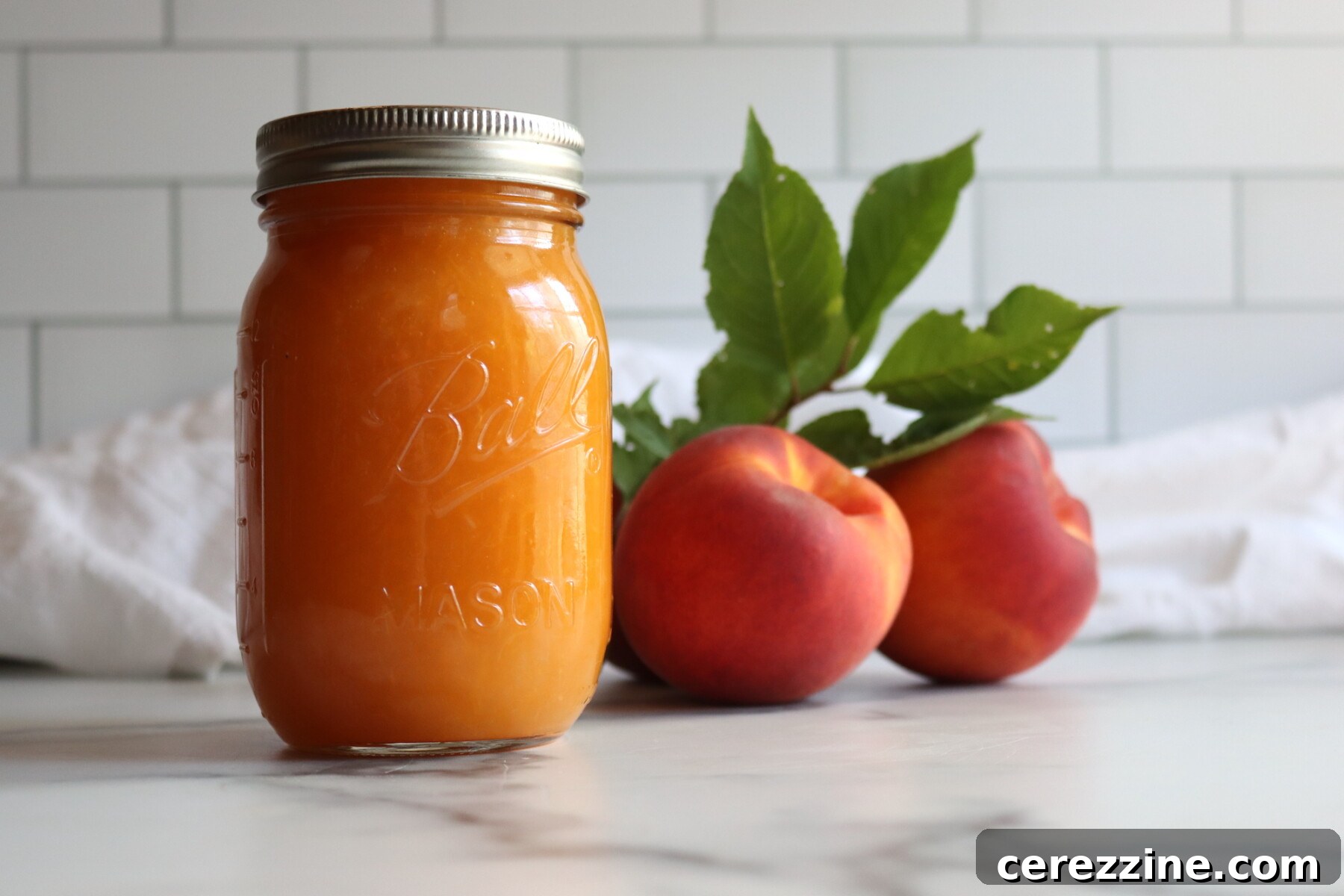 Peach applesauce in canning jars on a table with fresh peaches