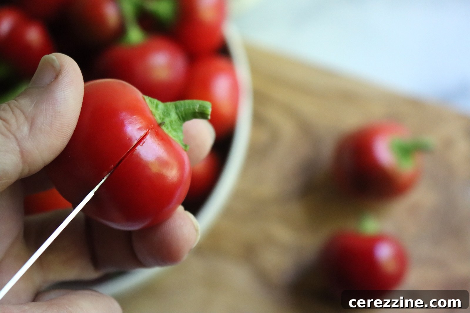 Cutting a slit in a cherry pepper with a paring knife