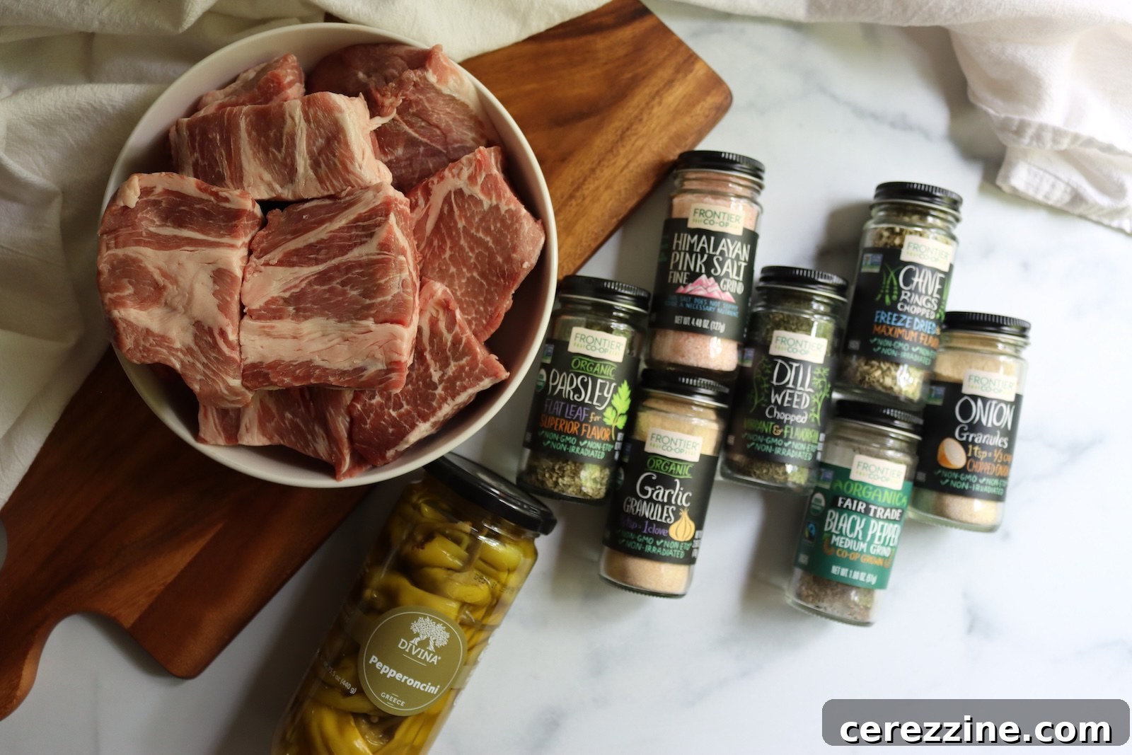 Cubed pork shoulder, sliced pepperoncini, and dried herbs and spices for canning Mississippi pork roast