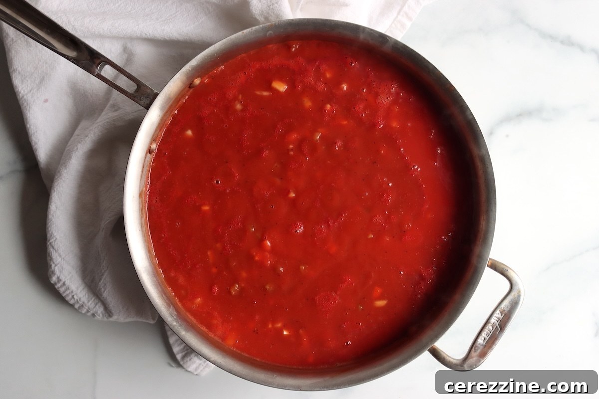 Italian-style tomato sauce cooking down in a stainless steel pan