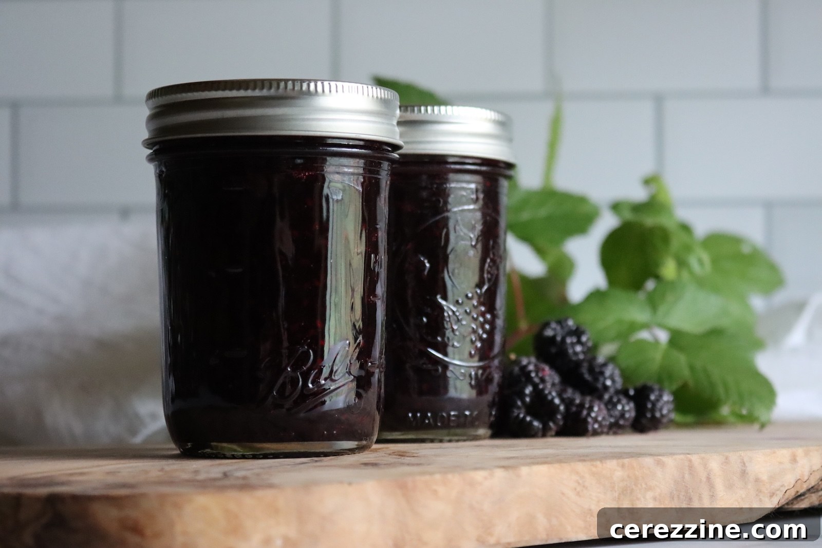 Two jars of black raspberry jam with fresh black raspberries