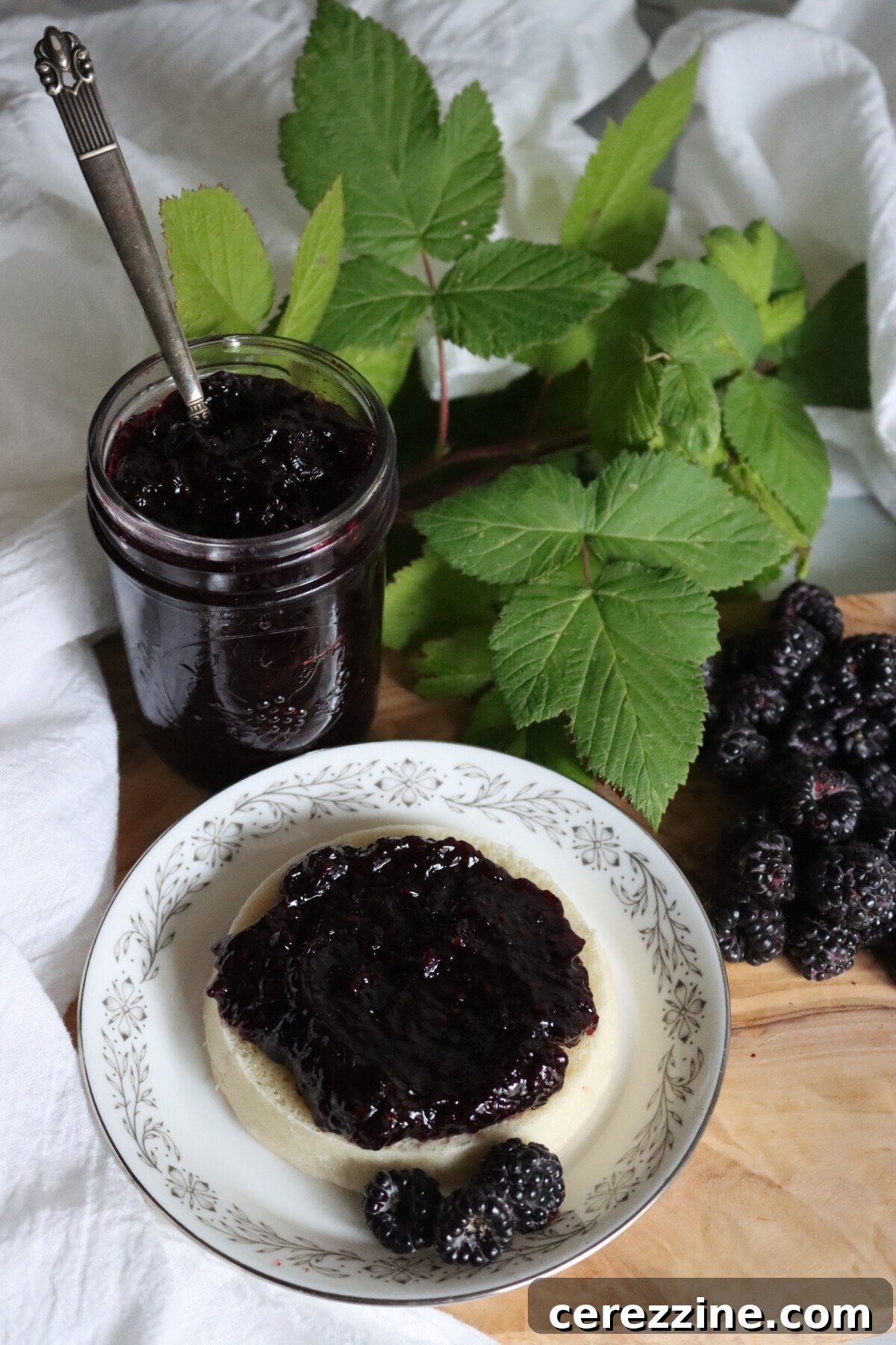 Open jar of black raspberry jam with jam spread on an English muffin