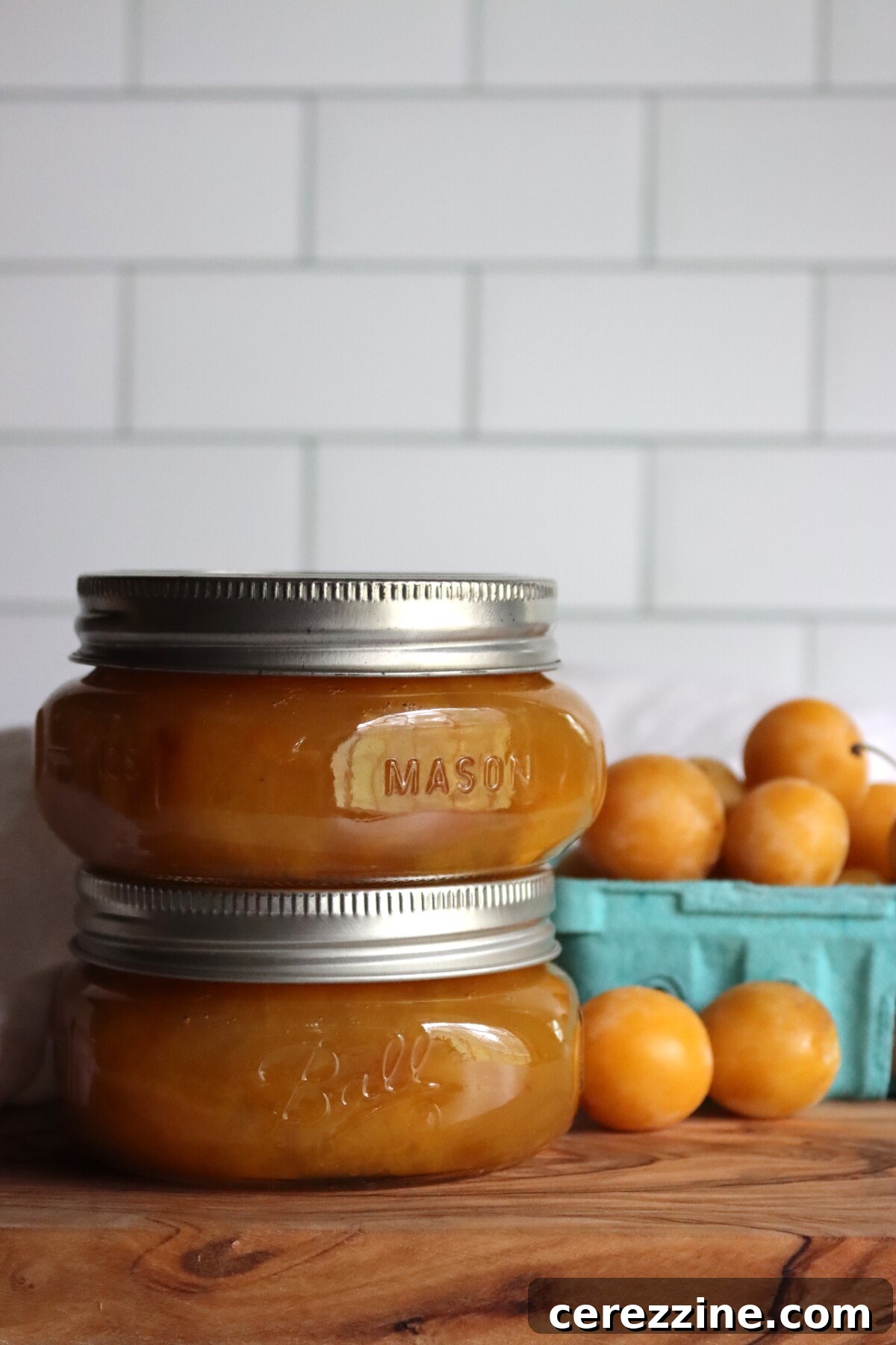 Two half-pint jars of mirabelle plum jam with fresh mirabelles
