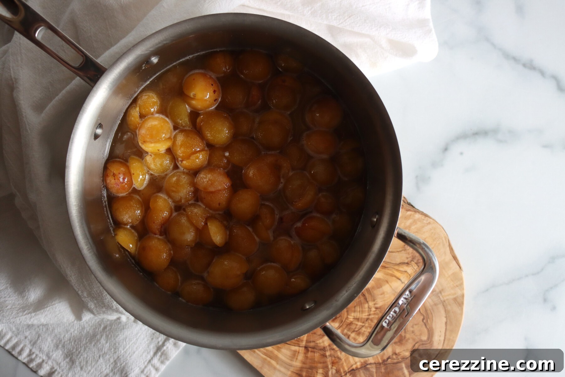 Halved mirabelle plums in a stainless steel pot, ready to cook into jam