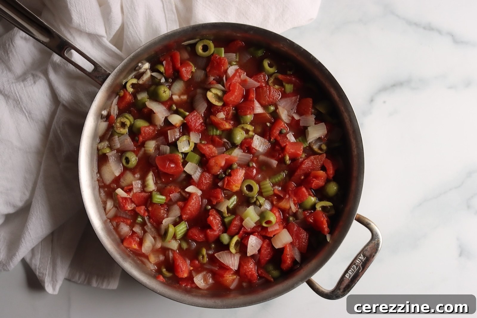 Tomatoes, green olives, and capers simmering with the onions and celery for caponata
