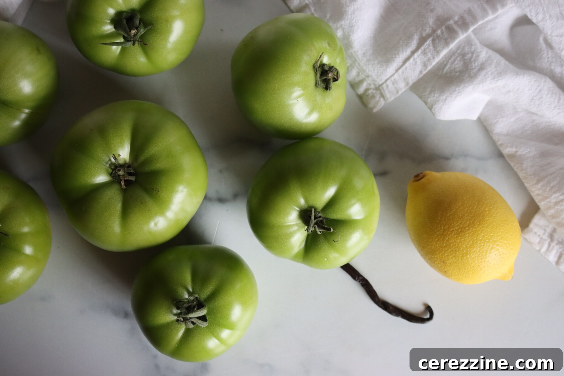 Green tomatoes, a lemon, and a vanilla bean for making Italian green tomato preserves